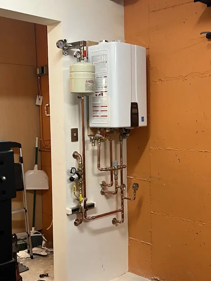 Plumbing technician inspecting water heater connections in East Vincent